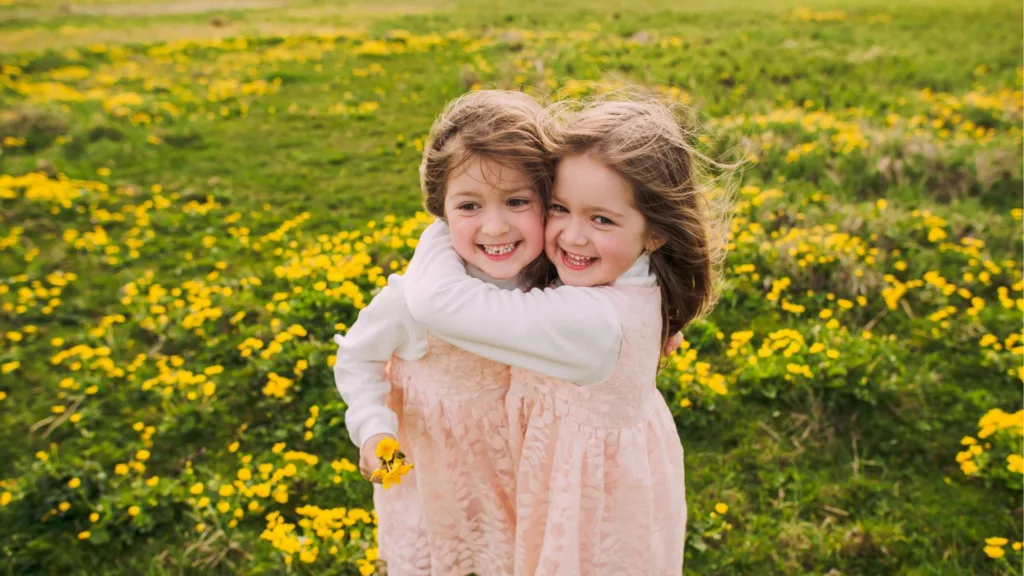 two little girls hug in a field of flowers celebrating national childrens dental health month